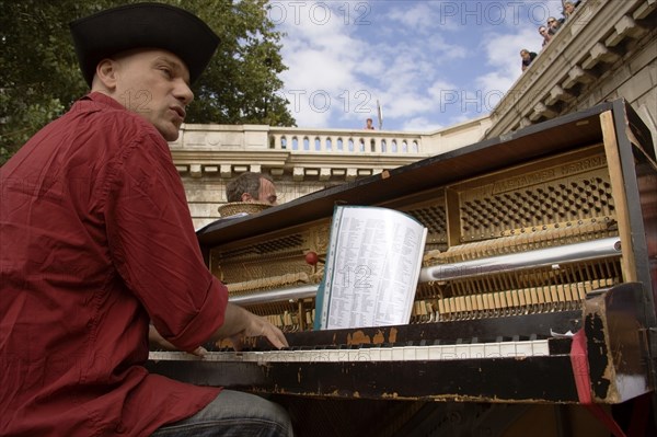 FRANCE, Ile de France, Paris, The Paris Plage urban beach. A singer playing a piano to an audience under the Pont Notre Dame on the Voie Georges Pompidou a usually busy road closed to traffic