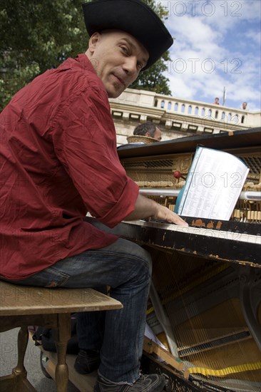 FRANCE, Ile de France, Paris, The Paris Plage urban beach. A singer playing a piano to an audience under the Pont Notre Dame on the Voie Georges Pompidou a usually busy road closed to traffic