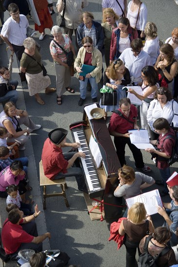 FRANCE, Ile de France, Paris, The Paris Plage urban beach. A singer playing a piano to an audience under the Pont Notre Dame on the Voie Georges Pompidou a usually busy road closed to traffic