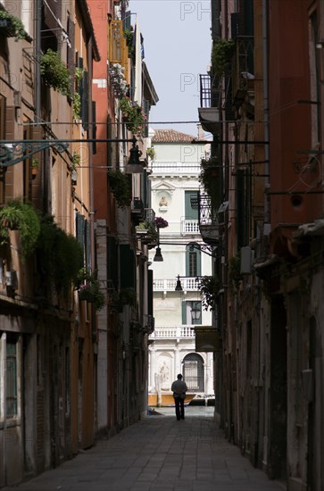 ITALY, Veneto, Venice, View down a narrow street to the Grand Canal in the San Polo and Santa Croce district with a man in silhouette by the canal