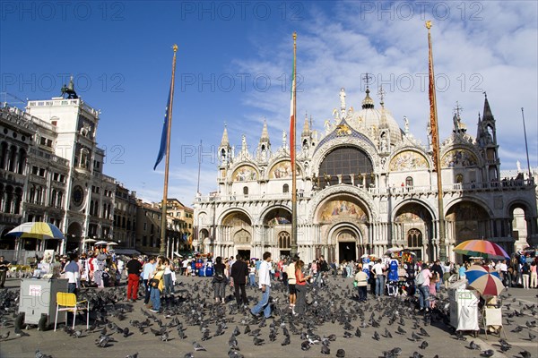 ITALY, Veneto, Venice, Tourists feeding pigeons in Piazza San Marco in front of St Marks Basilica