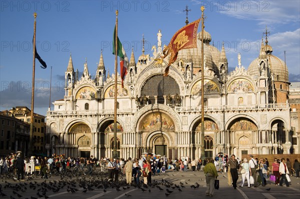 ITALY, Veneto, Venice, Tourists feeding pigeons in Piazza San Marco in front of St Marks Basilica
