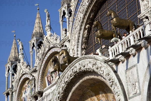 ITALY, Veneto, Venice, The bronze Horses of St Mark and the 17th Century mosaics on the facade of St Marks Basilica with tourists on the viewing balcony