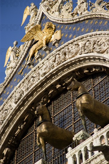 ITALY, Veneto, Venice, The bronze Horses of St Mark and the winged Lion of St Mark below Angels on the facade of St Marks Basilica