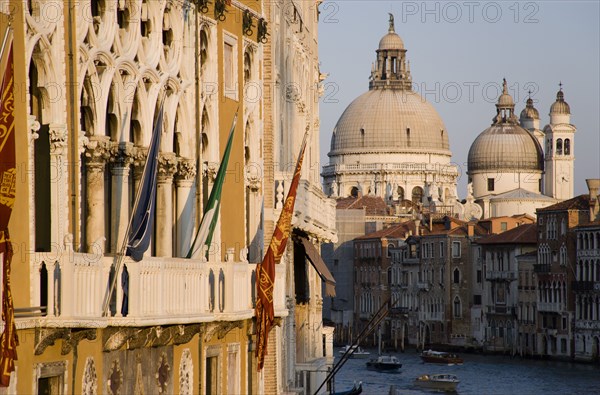 ITALY, Veneto, Venice, The Baroque church of Santa Maria della Salute on the Grand Canal. The Palazzo Franchetti Cavalli of Archduke Frederick of Austria on the left is decked with flags