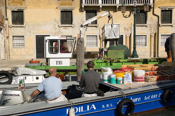 ITALY, Veneto, Venice, Painters and decorators wait to moor their boat on the Grand Canal whilst a refuse collection boat collects garbage