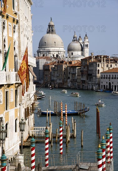 ITALY, Veneto, Venice, "The Byzantine church of Santa Maria della Salute with water taxis passing along the Grand canal towards Palazzo Franchetti Cavali decked with flags, the palace once owned by Archduke Frederick of Austria"