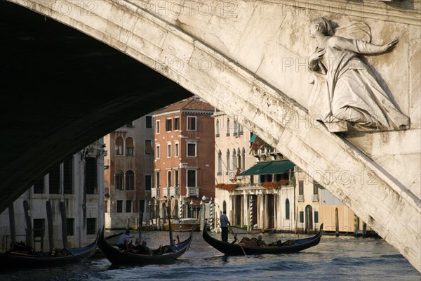 ITALY, Veneto, Venice, A gondola carrying tourists passes beneath the Rialto Bridge over the Grand Canal