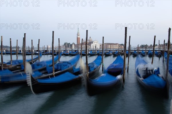 ITALY, Veneto, Venice, Gondolas moored at dusk in the Molo San Marco basin with Palladio's church of San Giorgio Maggiore on the island of the same name in the distance