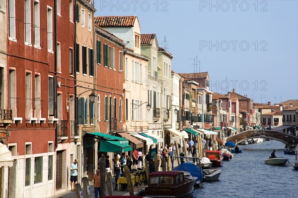 ITALY, Veneto, Venice, Tourists walking along the Fondamenta dei Vetrai with boats moored on the Rio dei Vetrai canal on the lagoon island of Murano