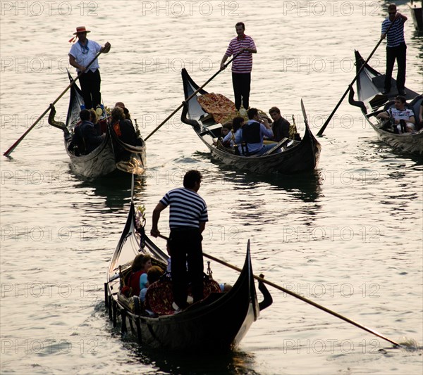 ITALY, Veneto, Venice, Gondoliers carrying sightseeing tourists on their gondolas at sunset on the Grand Canal