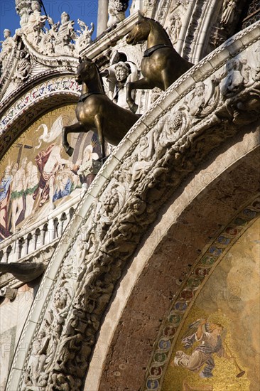 ITALY, Veneto, Venice, Two of the four bronze Horses of St Mark above the central doorway on the facade of the Basilica Can Marco with its 17th Century religious mosaics