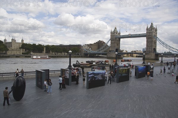 ENGLAND, London, The Queens walk open air exhibition outside the GLA city hall with Tower Bridge behind.