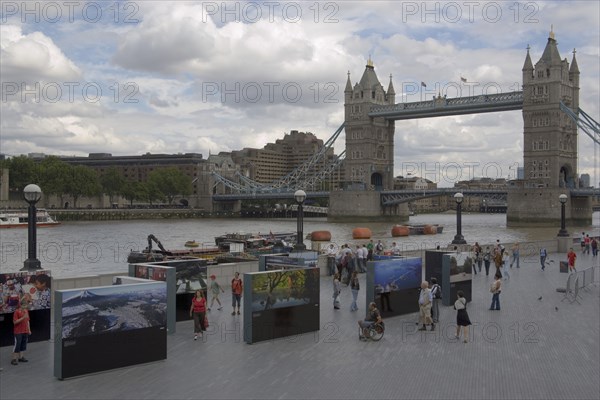 ENGLAND, London, The Queens walk open air exhibition outside the GLA city hall with Tower Bridge behind.