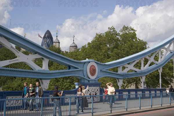ENGLAND, London, The Tower of London and the Gherkin seen through a detail of  Tower bridge with pedestrians crossing.