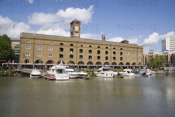 ENGLAND, London, St Catherine’s Dock with yachts moored next to the former warehouses which are now luxury apartments.
