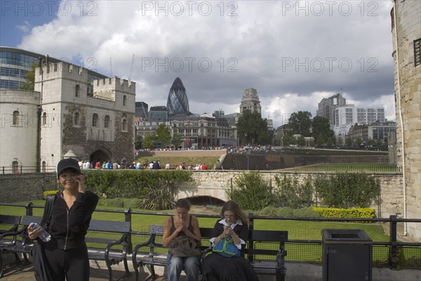 ENGLAND, London, Tourists using their mobile phone outside the Tower of London with the Gherkin Building behind.