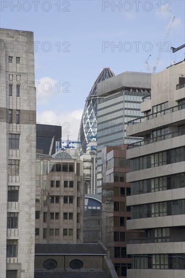 ENGLAND, London, "The Gherkin Swiss Re building seen, through tightly huddled buildings in the city, from London Bridge."