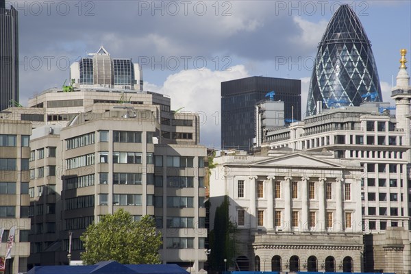 ENGLAND, London, "The Gherkin Swiss Re building seen, through tightly huddled buildings in the city, from London Bridge."