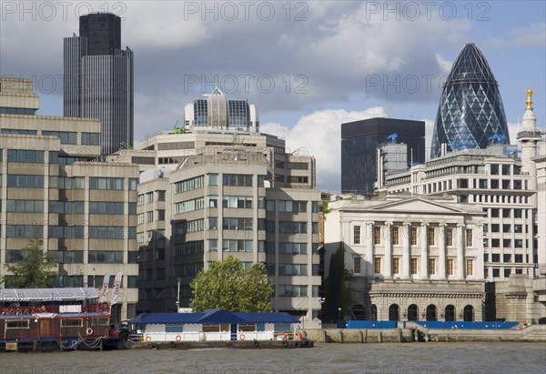 ENGLAND, London, "The Gherkin Swiss Re building seen, through tightly huddled buildings in the city, from London Bridge."
