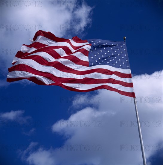 USA, Flags, American Stars and Stripes National Flag blowing in the wind against a blue sky with clouds