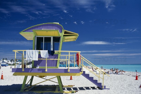 USA, Florida, Miami, South Beach. Colourful Lifeguard Station on sandy beach with sunbathers near turquoise sea