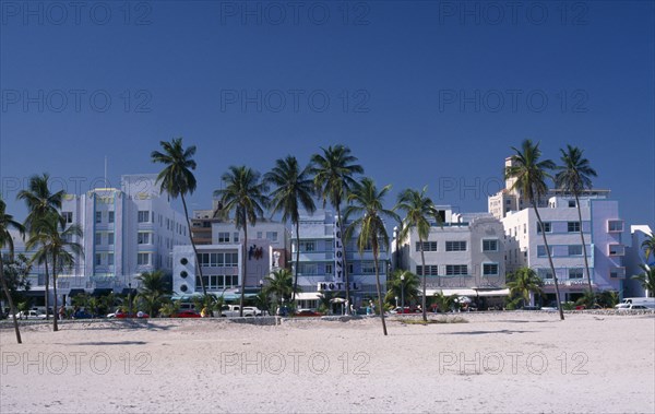 USA, Florida, Miami , South Beach. View across sandy beach with palm trees towards Ocean Drive Art Deco hotel facades