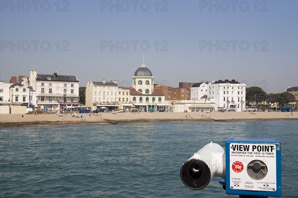 ENGLAND, West Sussex, Worthing, View from the pier across the sea towards The Dome Cinema and Marine Parade cafes. Viewing telescope in the foreground.