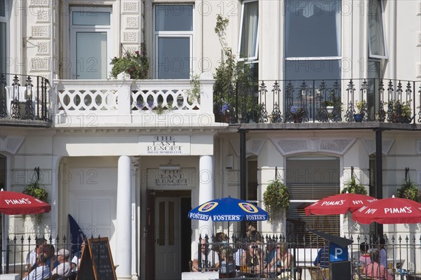 ENGLAND, West Sussex, Worthing, The Last Resort seafront bar exterior with people sitting under parasols drinking
