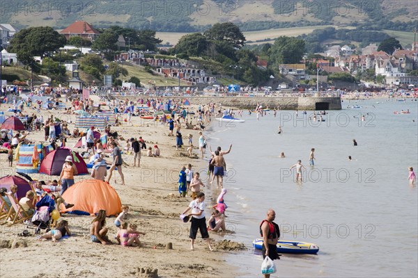 ENGLAND, Dorset, Swanage Bay, View along the shoreline of sandy beach with sunbathers on the sand and swimming in the sea
