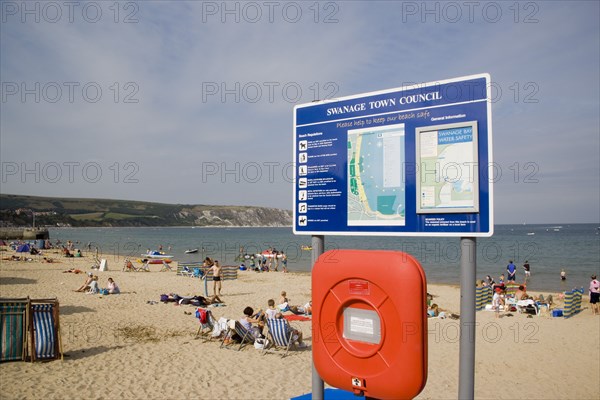 ENGLAND, Dorset, Swanage Bay, Town Council tourist information sign with busy sandy beach behind