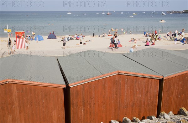 ENGLAND, Dorset, Swanage Bay, View across beach hut roofs towards busy sandy beach and sea