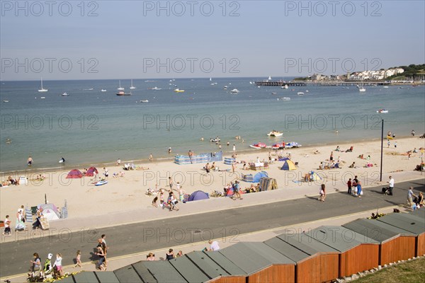 ENGLAND, Dorset, Swanage Bay, Elevated view over beach huts towards busy stretch of sandy beach and sea