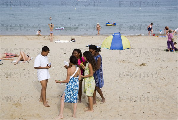 ENGLAND, Dorset, Swanage Bay, A group of children eating ice cream on sandy beach