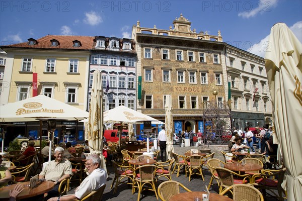 CZECH REPUBLIC, Bohemia, Prague, Old Town. People sitting at tables with umbrellas at street cafe in Male Namesti