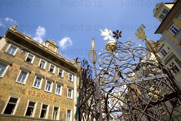 CZECH REPUBLIC, Bohemia, Prague, "Old Town. Water fountain with ornate metalwork around it in Male Namesti with U Rott, now Hotel Rott, behind it. The building facade is decorated with murals by the 19th Century artist Mikulas Ales "