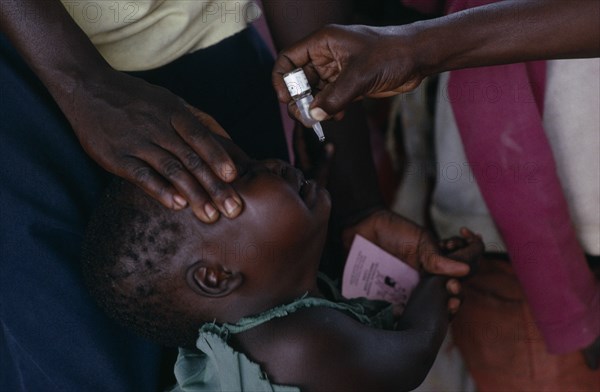 UGANDA, Medical, Health worker administering immunization polio drops to child in area near Gulu.  Partly funded by Comic Relief.
