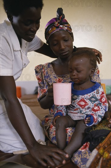 UGANDA, Medical, Nurse comforting mother with child with malaria in hospital in Orukinga refugee camp near the Rwandan border.
