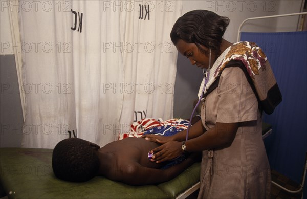 UGANDA, Kampala, Female doctor examining boy in Kawempe clinic.