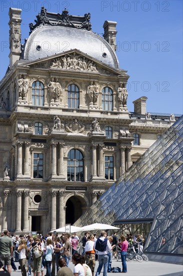 FRANCE, Ile de France, Paris, Tourists outside the pyramid entrance to the Musee du Louvre beside the Richelieu Pavilion