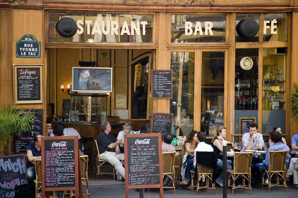 FRANCE, Ile de France, Paris, Montmartre People at tables on the pavement outside a cafe in the Rue Yvonne le Tac