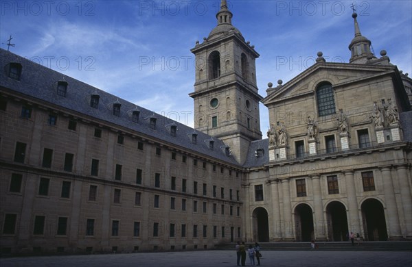 SPAIN, Madrid, El Escorial, San Lorenzo El Escorial palace and monastery complex built by Felipe II.  Exterior view with tourist visitors standing in square in foreground.