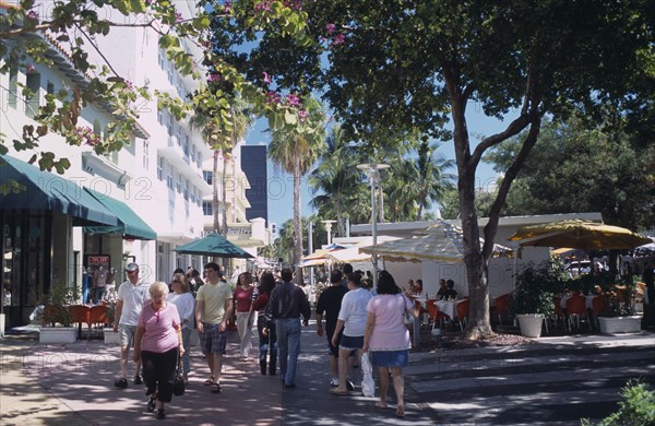 USA, Florida, Miami, South Beach. Lincoln Avenue. People walking under trees on pedestrian promenade lined with shops and street cafes near The Lincoln Theatre