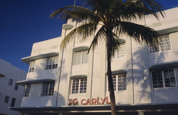 USA, Florida, Miami, South Beach. Ocean Drive. The Carlyle Hotel seen in early morning light with a palm tree casting a shadow on the exterior