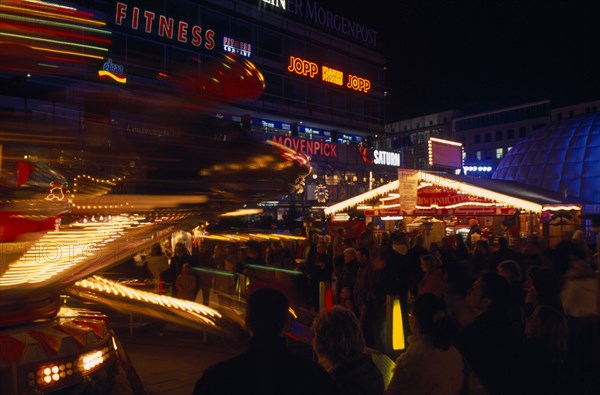 GERMANY, Berlin, Breitscheidplatz. Christmas Market. Funfair and stalls colourfully Illuminated at night with people gathered around.