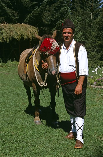 BULGARIA, Chalin Valog, "Man in national costume standing with horse. Pirin Mountain, near Bansko,. "