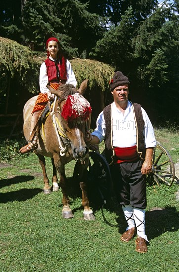 BULGARIA, Chalin Valog, "Man and girl in national costume with horse, Pirin Mountain, near Bansko."