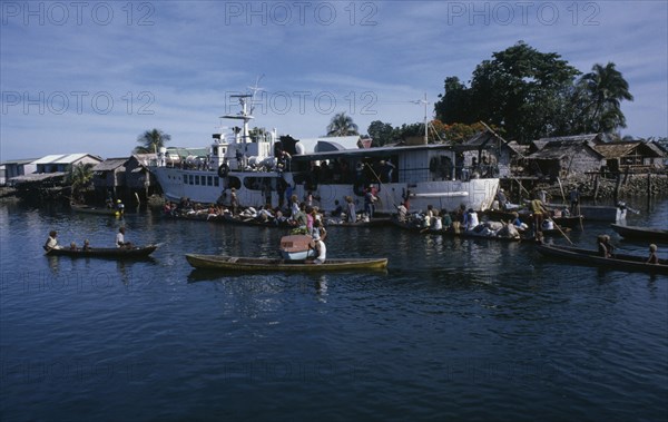 PACIFIC ISLANDS, Melanesia, Solomon Islands, "Malaita Province, Lau Lagoon. Weekly boat service visiting Foueda Island attracting crowds in canoes.  Thatched housing behind.  "