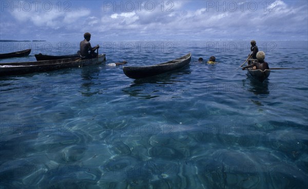 PACIFIC ISLANDS, Melanesia, Solomon Islands, "Malaita Province, Lau Lagoon. Spear fishing from wooden dug out canoes.  Dark turquoise sea with light reflections and blue sky."