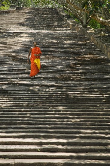 SRI LANKA, Mihintale, "A lone monk descending The Stairway, 1840 granite steps that lead up to the dagobas and shrines at the top of the hill."